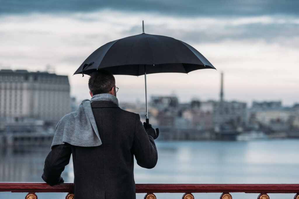 A man holding an umbrella to stay dry. If you need an extra layer of coverage then you should consider getting an umbrella insurance policy. Chastain Otis Insurance Agency can help you.