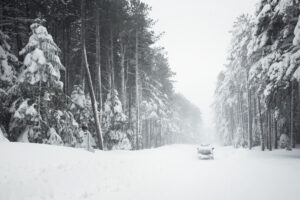 A vehicle drives down a snow-covered road.